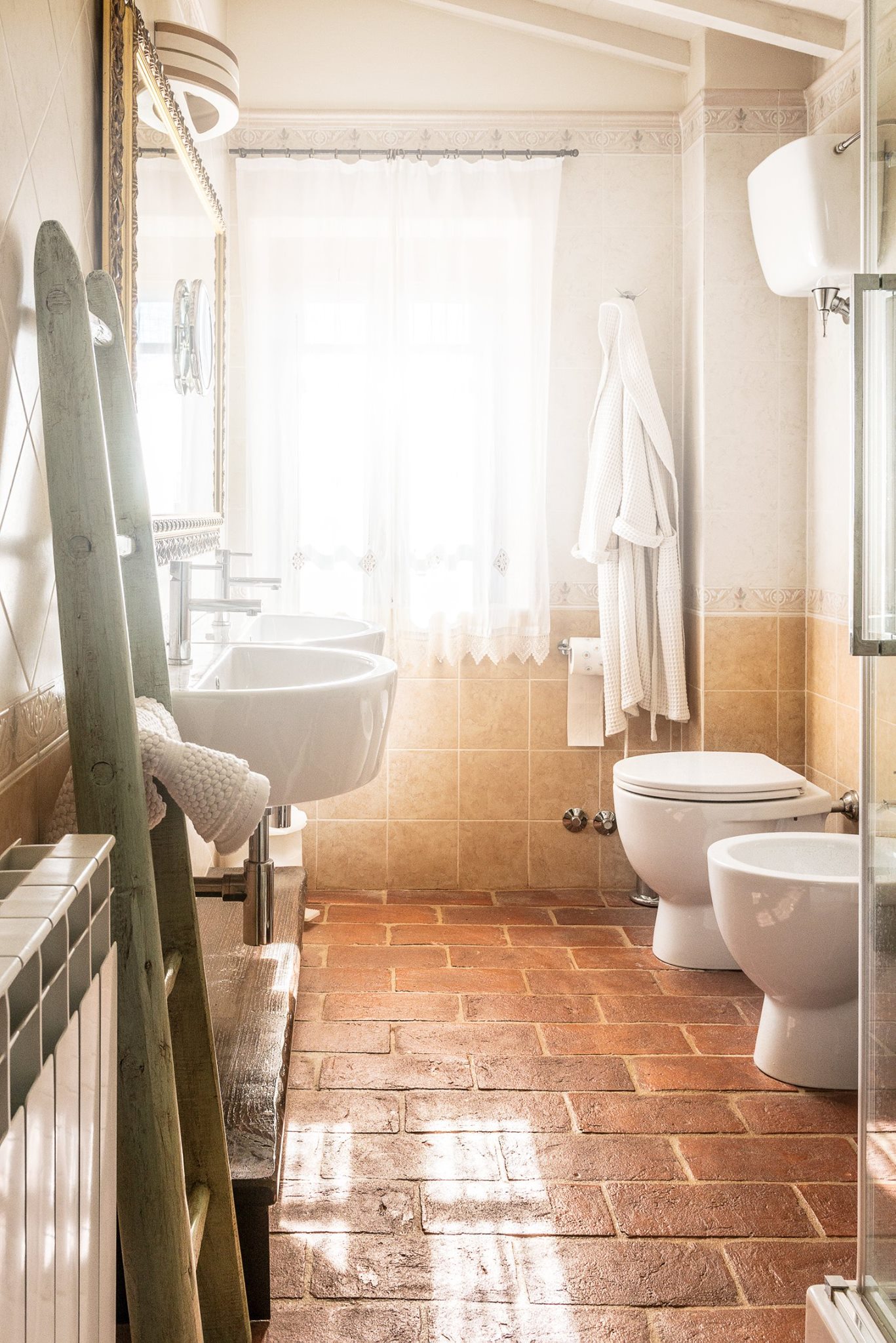 Bagno in cotto con doccia, accappatoio e luce naturale
