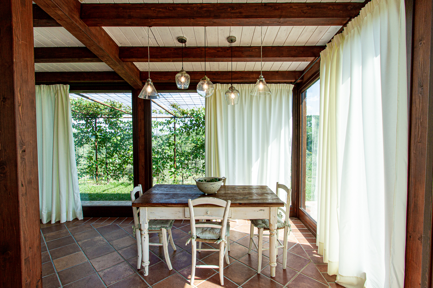 Sala da pranzo con travi a vista e vetrate sul verde
